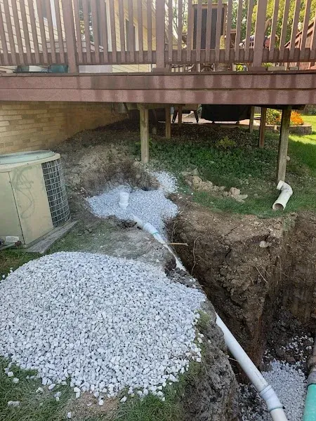Excavated residential yard with drainage pipe and gravel during installation